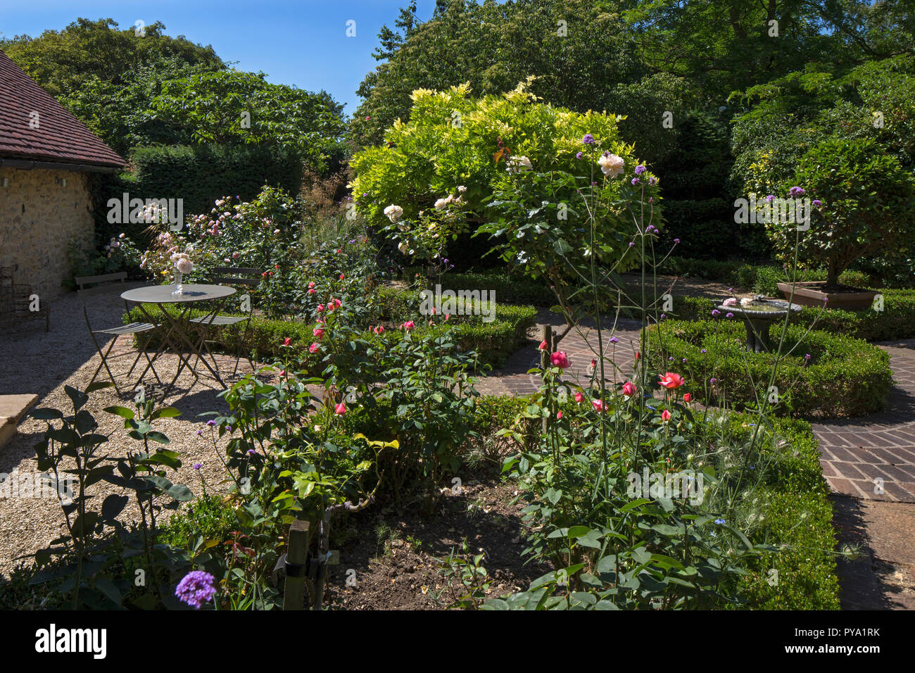 Tavolo in metallo e sedie nel giardino di rose con box coperture in english country garden,l'Inghilterra,l'Europa Foto Stock