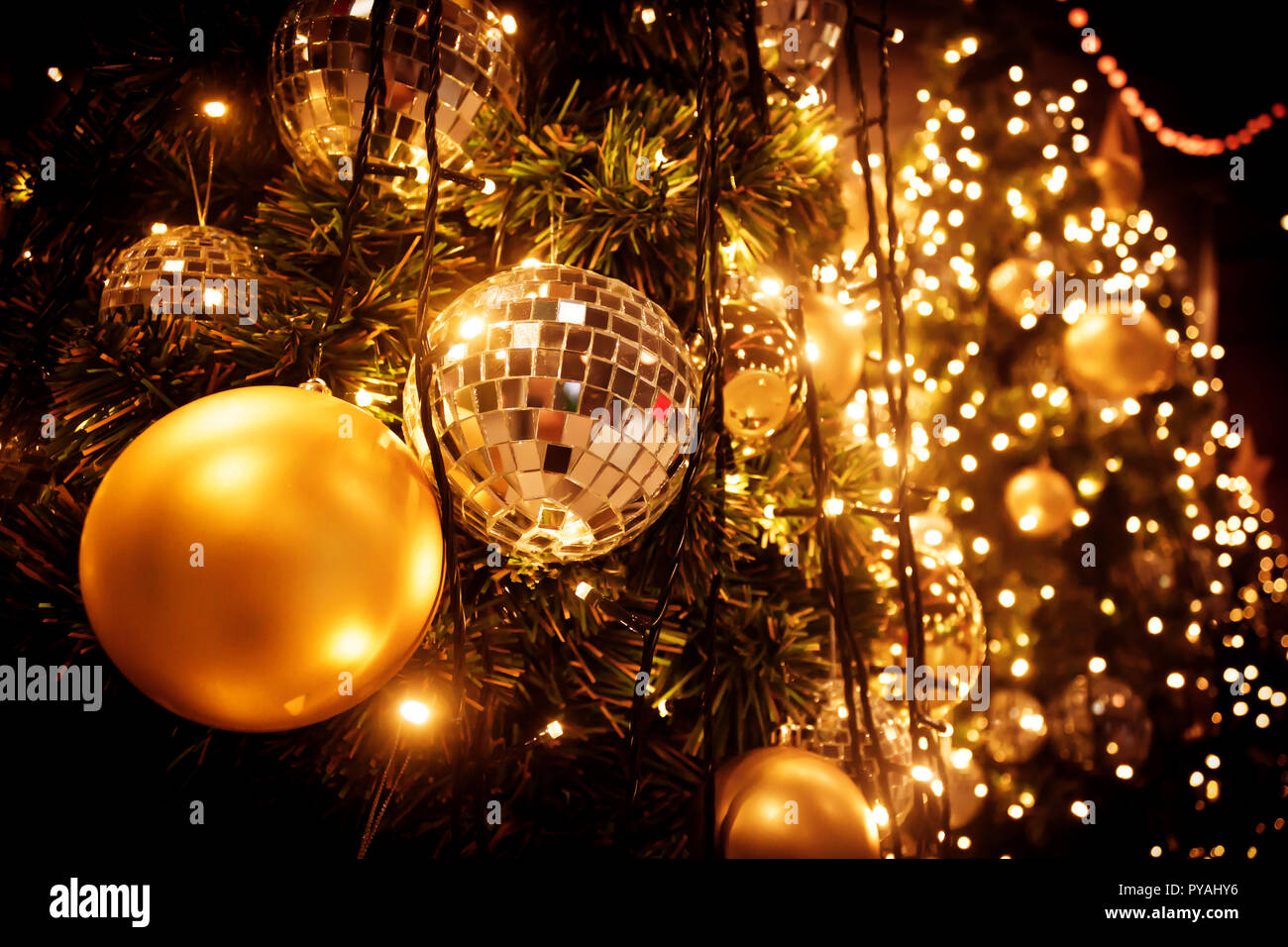 Albero di natale con sfera in oro e luci bokeh sfondo. Xmas abstract close up con decorazioni incandescente all'esterno. Foto Stock