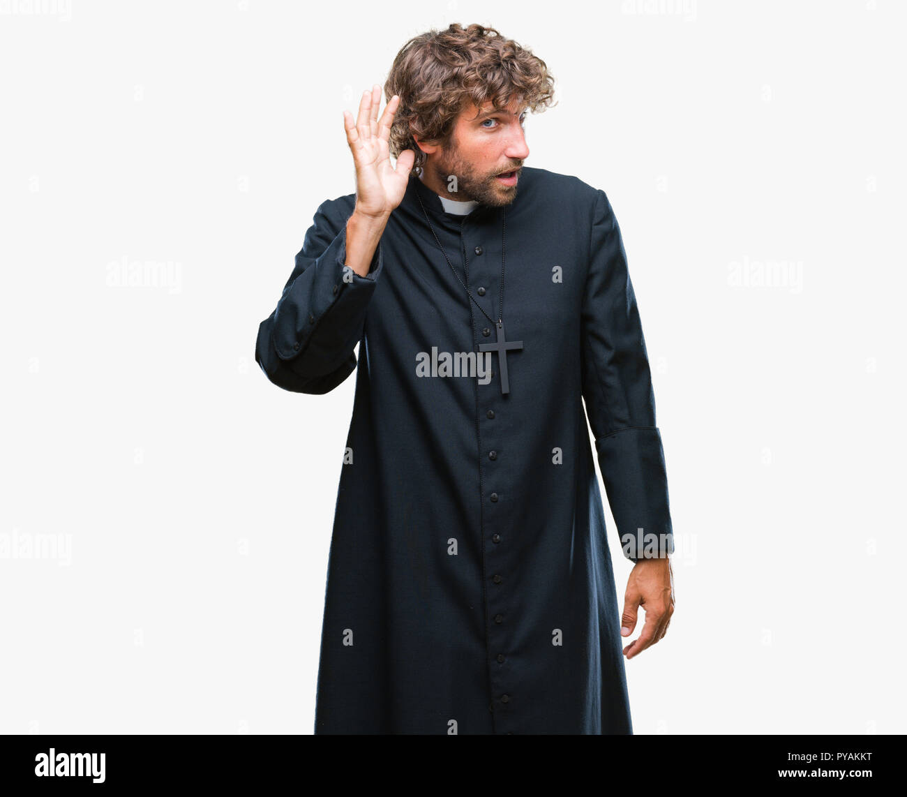 Bello ispanica sacerdote cattolico uomo sullo sfondo isolato sorridente con la mano sul orecchio in ascolto di un audizione di rumor o gossip. Concetto di sordità. Foto Stock