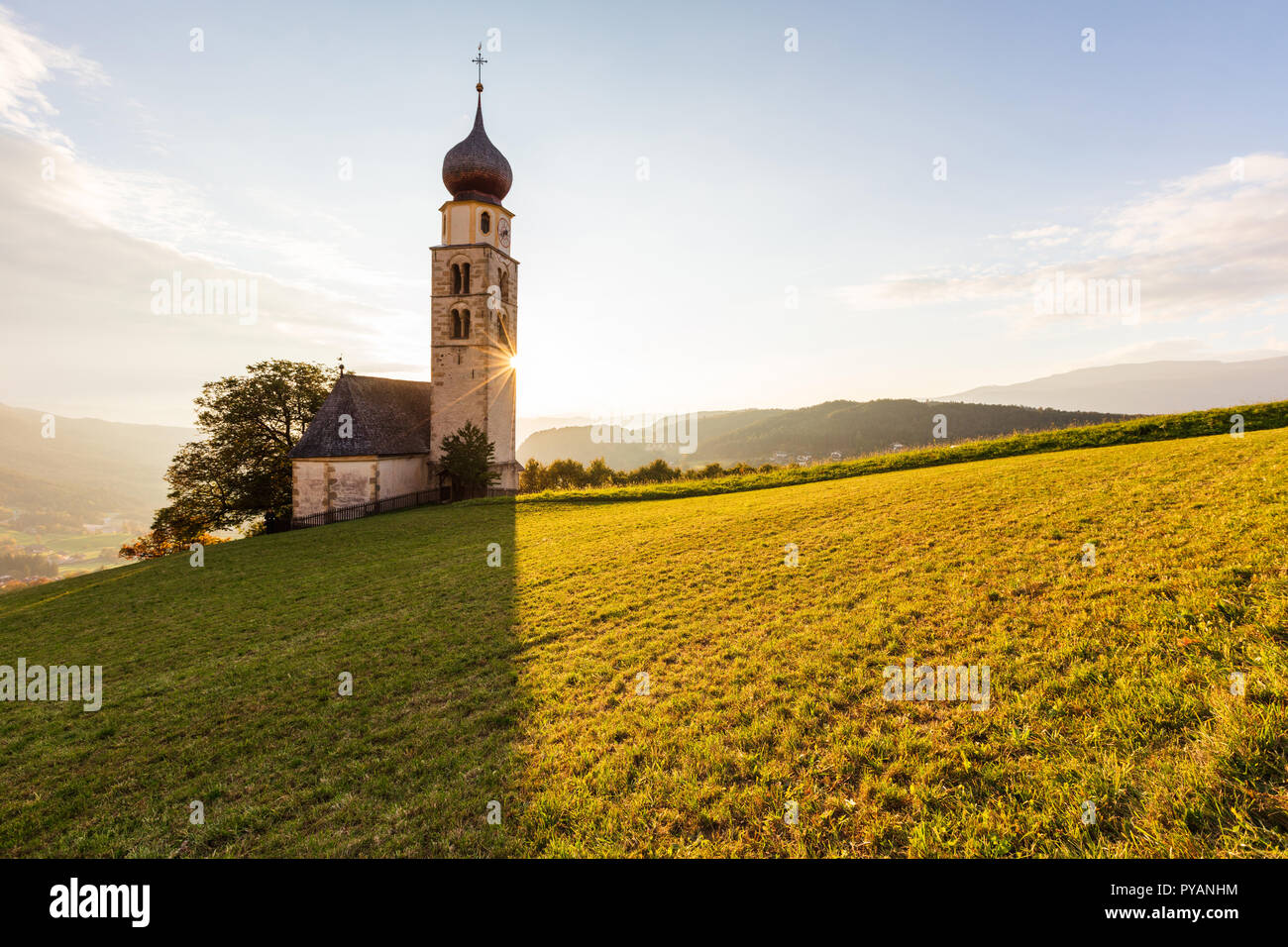 Cappella in remoto con un alta torre campanaria nel bel mezzo di un verde prato di montagna Foto Stock