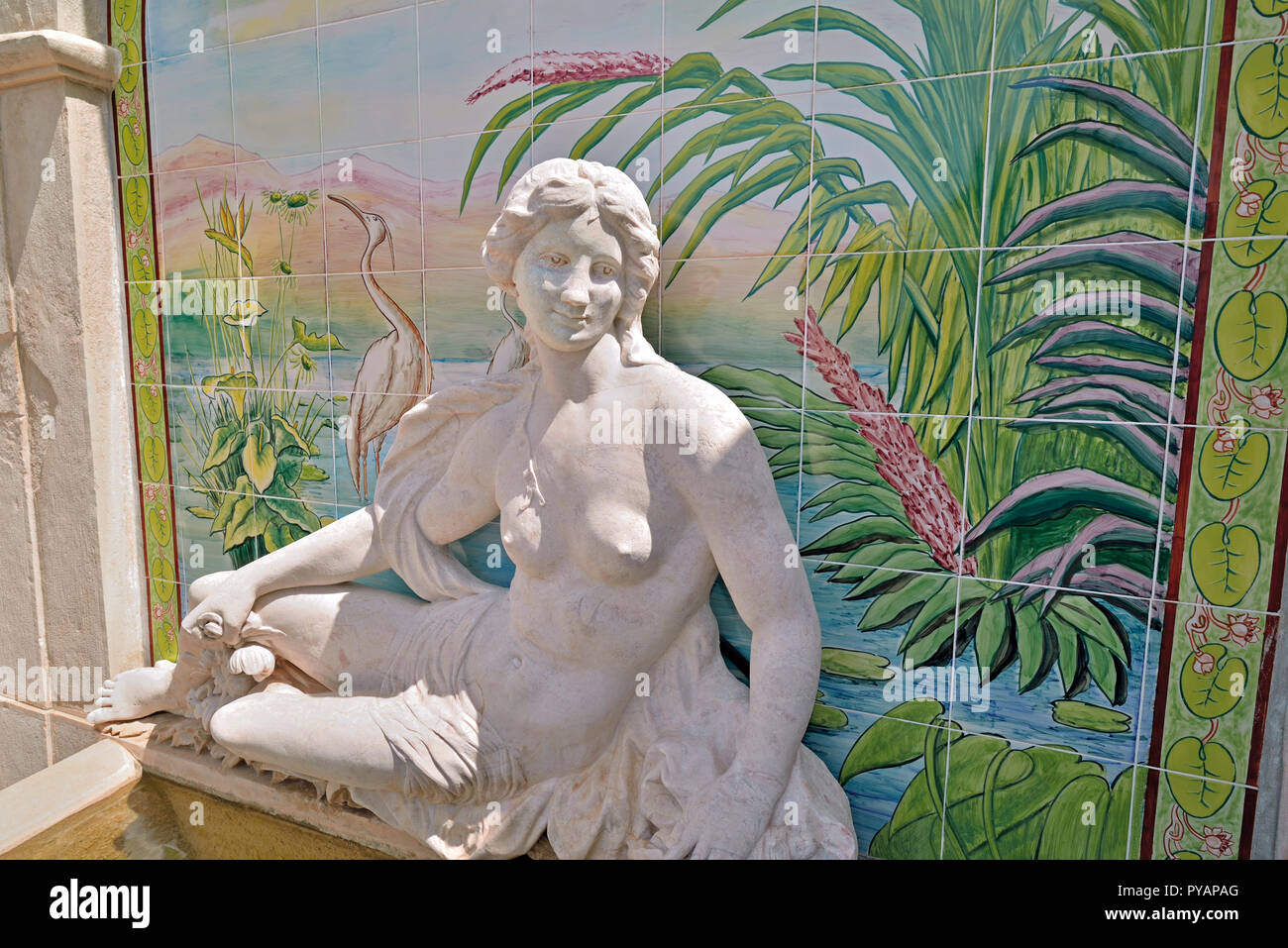 Statua di figura mitologica di fronte piastrelle dipinte con scenario esotico Foto Stock