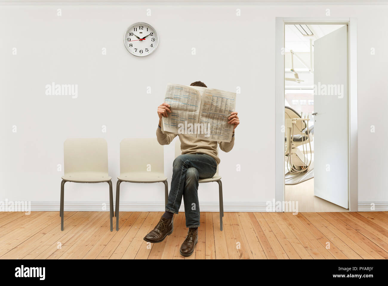 Medical sala di attesa con una persona seduta quotidiano di lettura Foto Stock