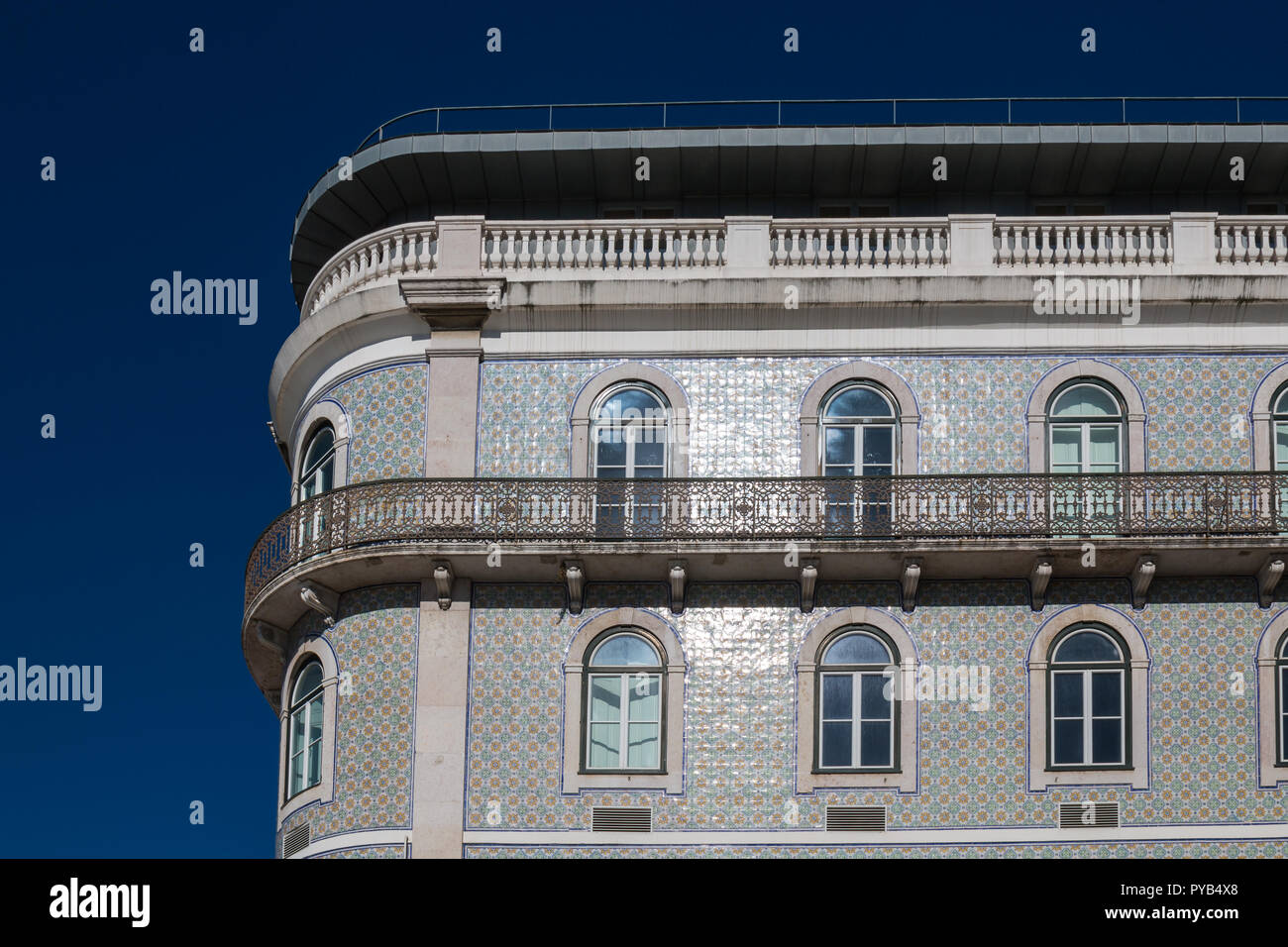 Tipica architettura portoghese con un angolo arrotondato. Casa con piastrelle in ceramica, finestre con archi e un grande balcone ornamentali. Blue sky. Lisbona, Po Foto Stock