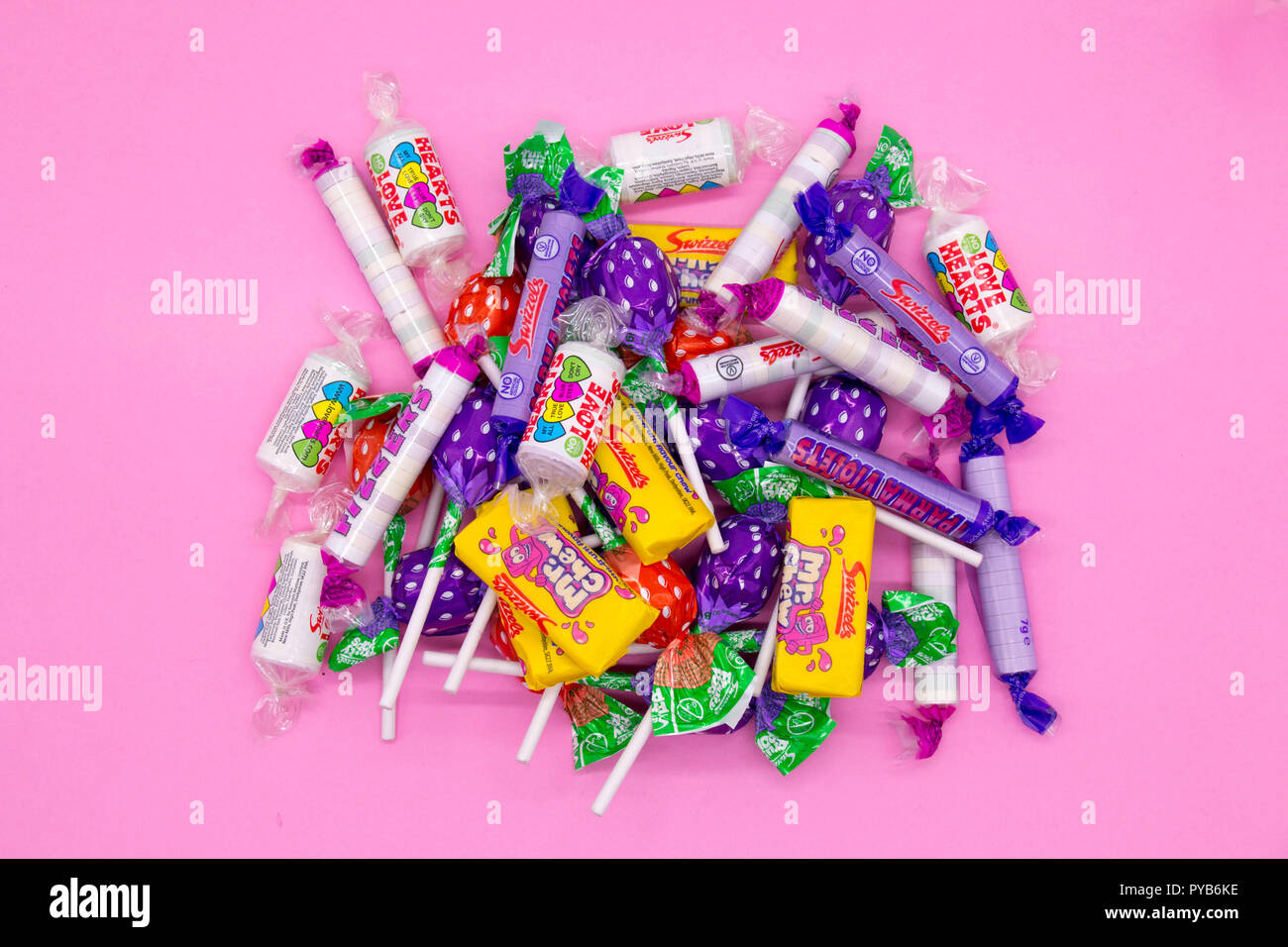 Swizzels negozio di dolci preferiti su un sfondo rosa con cuori, pop per lecca-lecca, parma violette, fizzers, bacchette, rinfrescare Foto Stock