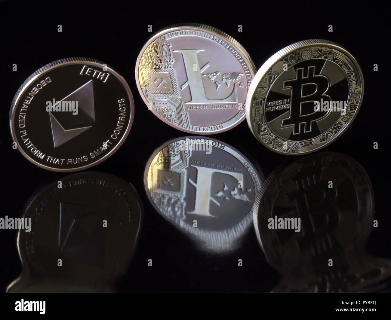 Il 30 agosto 2018, Berlino: 30 agosto 2018, Germania Berlino: un (L-R) Etherum classico coin con l impronta 'ETH', una lite monete e una moneta Bitcoin con l impronta "eccesso di potere in Numeris' (forza in numeri) sono riflesso distorto in una superficie nera. La valuta digitale Bitcoin è stata intorno per dieci anni e ora è basato su blockchains (catene di blocchi di dati), in cui le unità di Bitcoin sono generati in operazioni matematiche su computer. Dopo Bitcoin, Internet Etherum valuta è il secondo più grande virtuale metodo di pagamento. Foto: Soeren Stache/dpa-Zentralbild/ZB Foto Stock