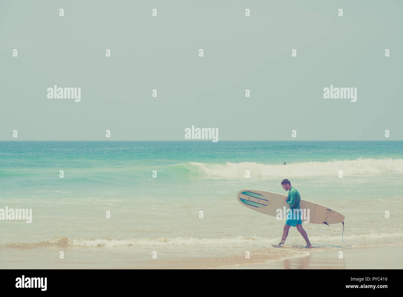 Hikkaduwa Lo Sri Lanka. Marzo 06, 2018. Un surfista passeggiate lungo la spiaggia con una tavola da surf. Foto Stock