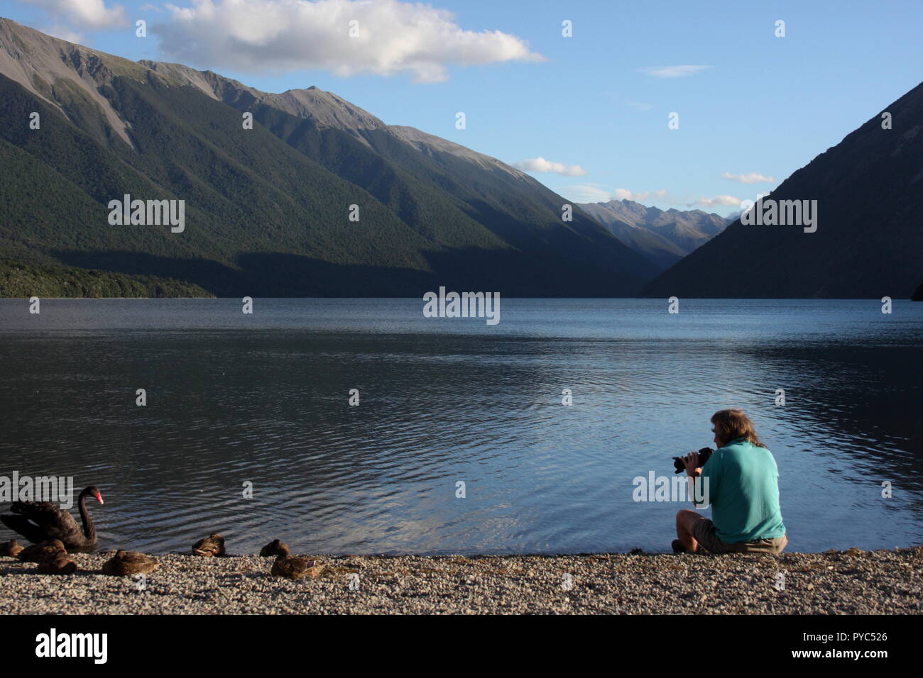 Lago Rotoiti, Nelson Lakes National Park, Nuova Zelanda, con un fotografo seduto a terra a scattare foto di uccelli Foto Stock