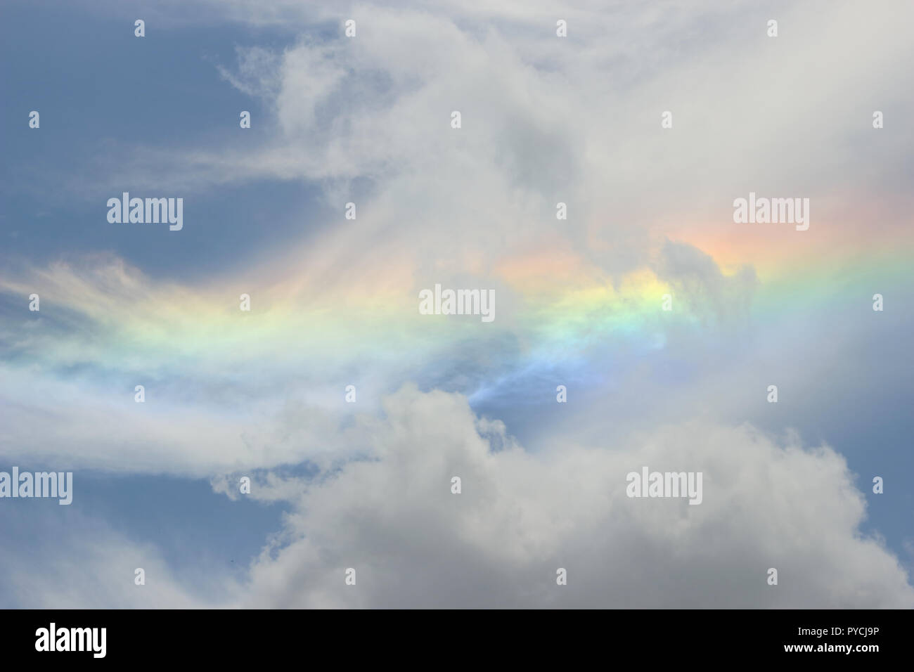 Un capolavoro celeste, dove un vibrante arcobaleno danzava in mezzo a un mare di nuvole di cottonia. Foto Stock