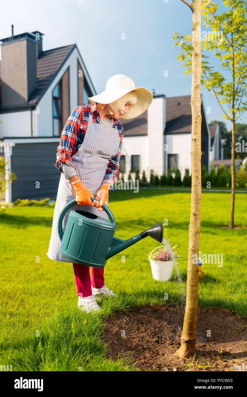 Piacevole bella donna di impianti di irrigazione in giardino Foto Stock
