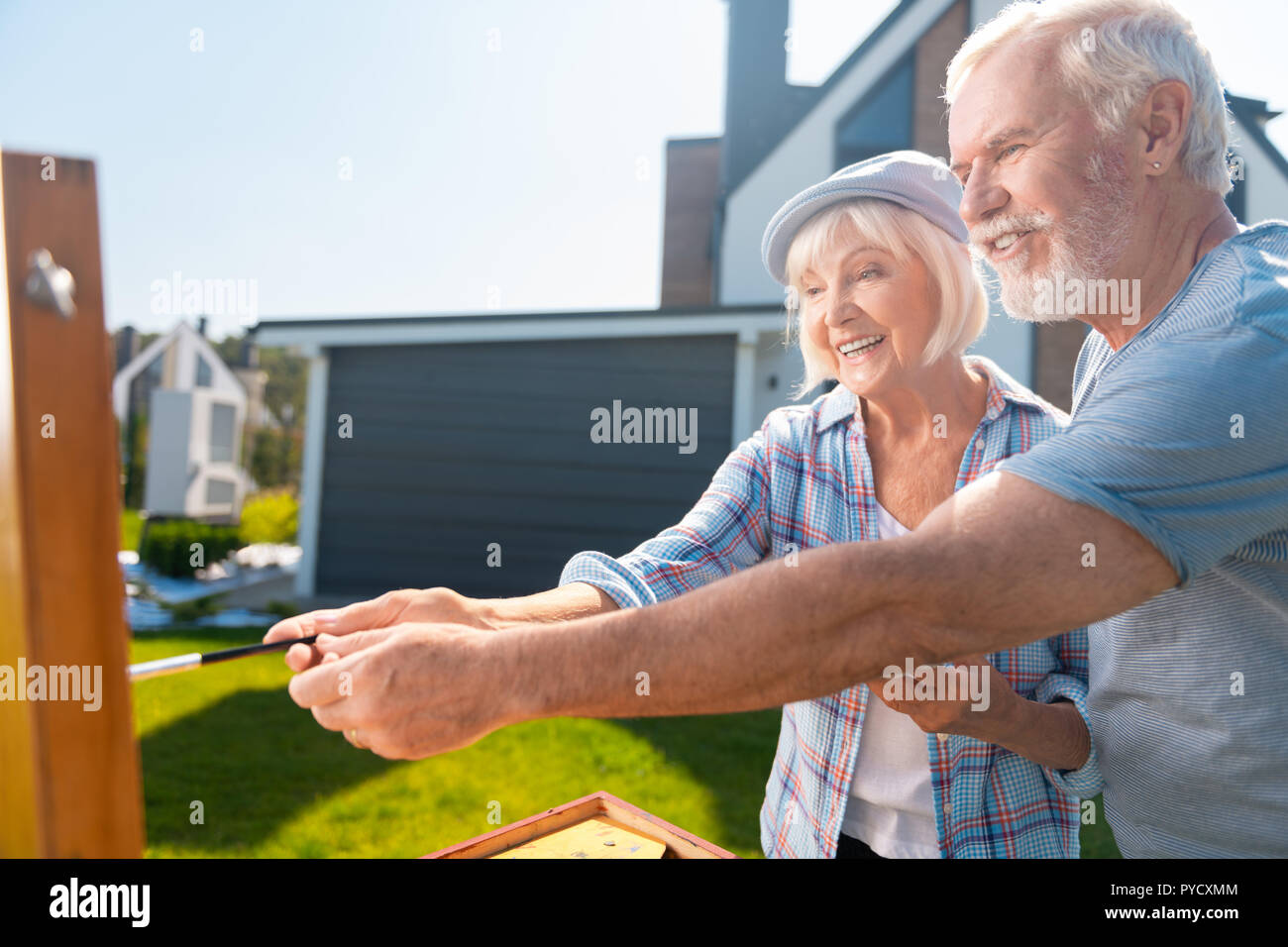Anziani moglie e marito tenendo una spazzola insieme mentre si disegna la loro casa Foto Stock