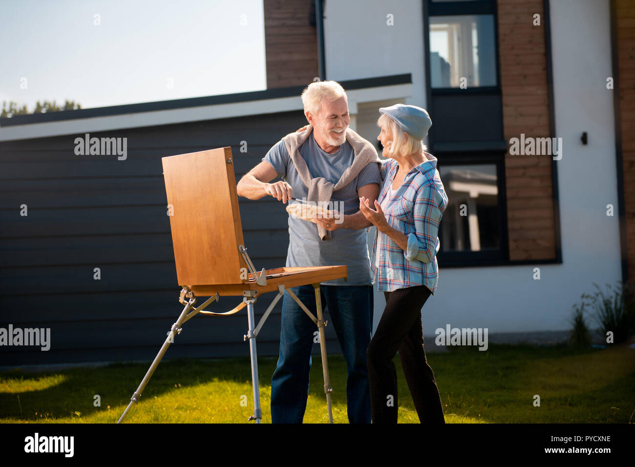 Biondo e pensionati donna che indossa blue hat proveniente da suo marito disegno Foto Stock