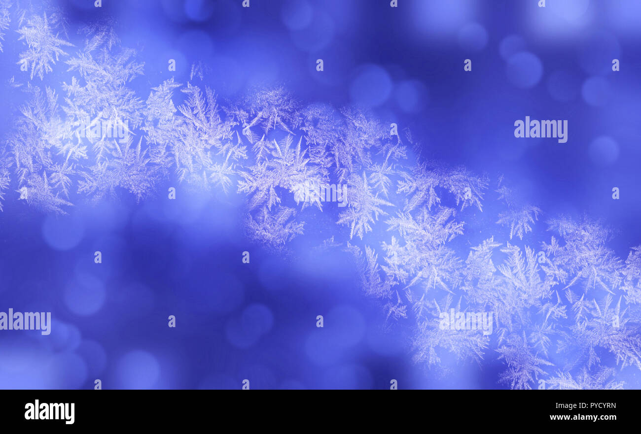 Inverno fiocchi di neve lucido sfondo sfocato in azzurro colori bianco. Sfocate sullo sfondo di Natale con fiocchi di neve, frost pattern, soffici luci flare Foto Stock