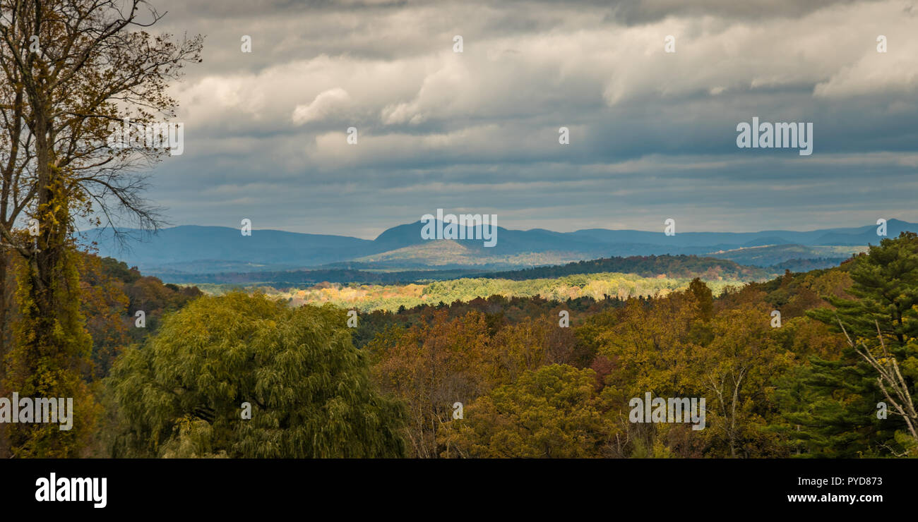 Rottura sole attraverso il cloud per gettare luce sulla caduta delle foglie sul New England Hillside Foto Stock