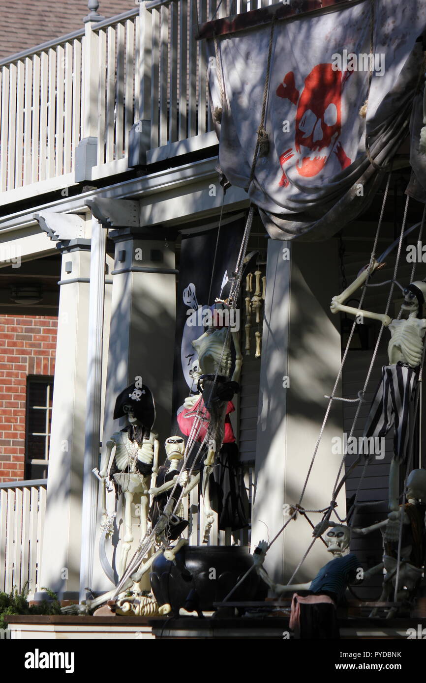 Scheletri pirata scalata verso il lato di una nave pirata o una casa come creativi Halloween decorazioni di prato. Foto Stock