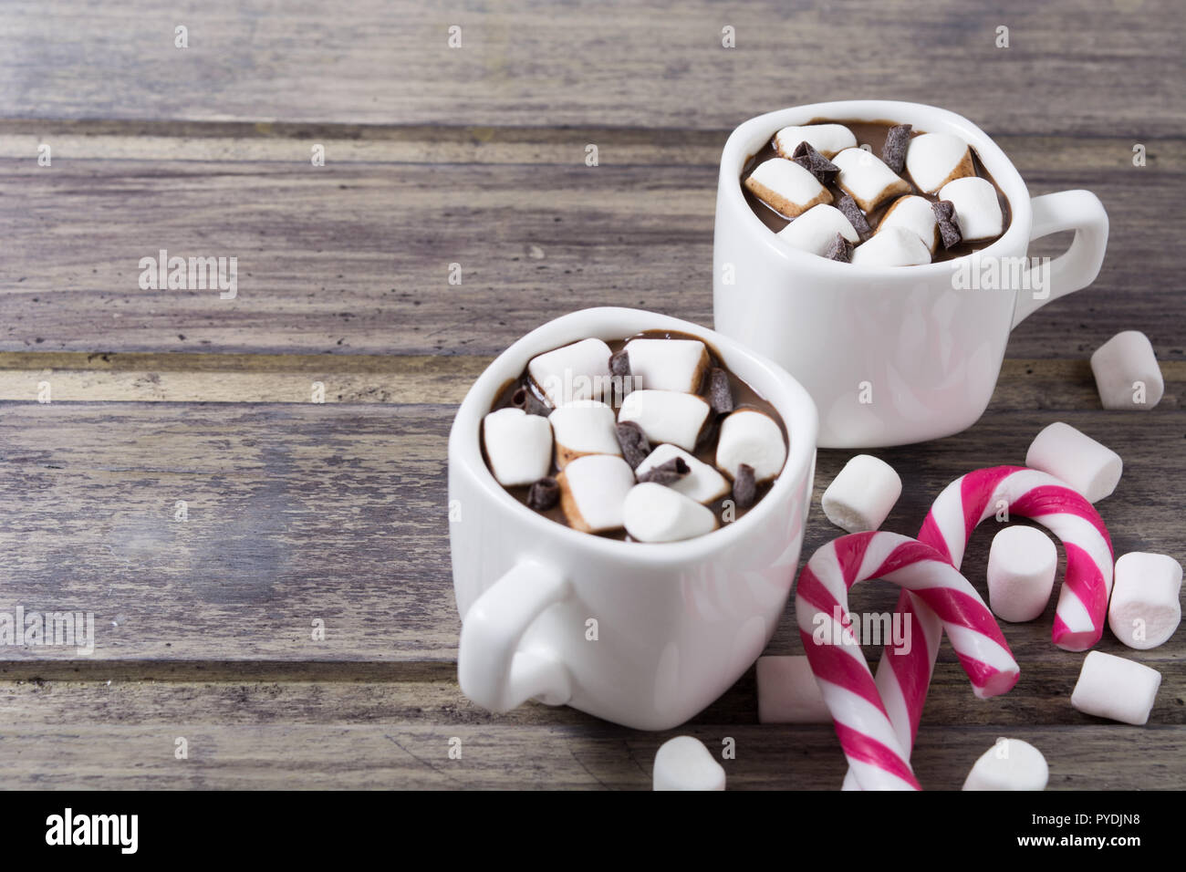 Due bicchieri di bianco con cioccolata calda e marshmallow sullo squallido tavolo in legno. Spazio di copia Foto Stock