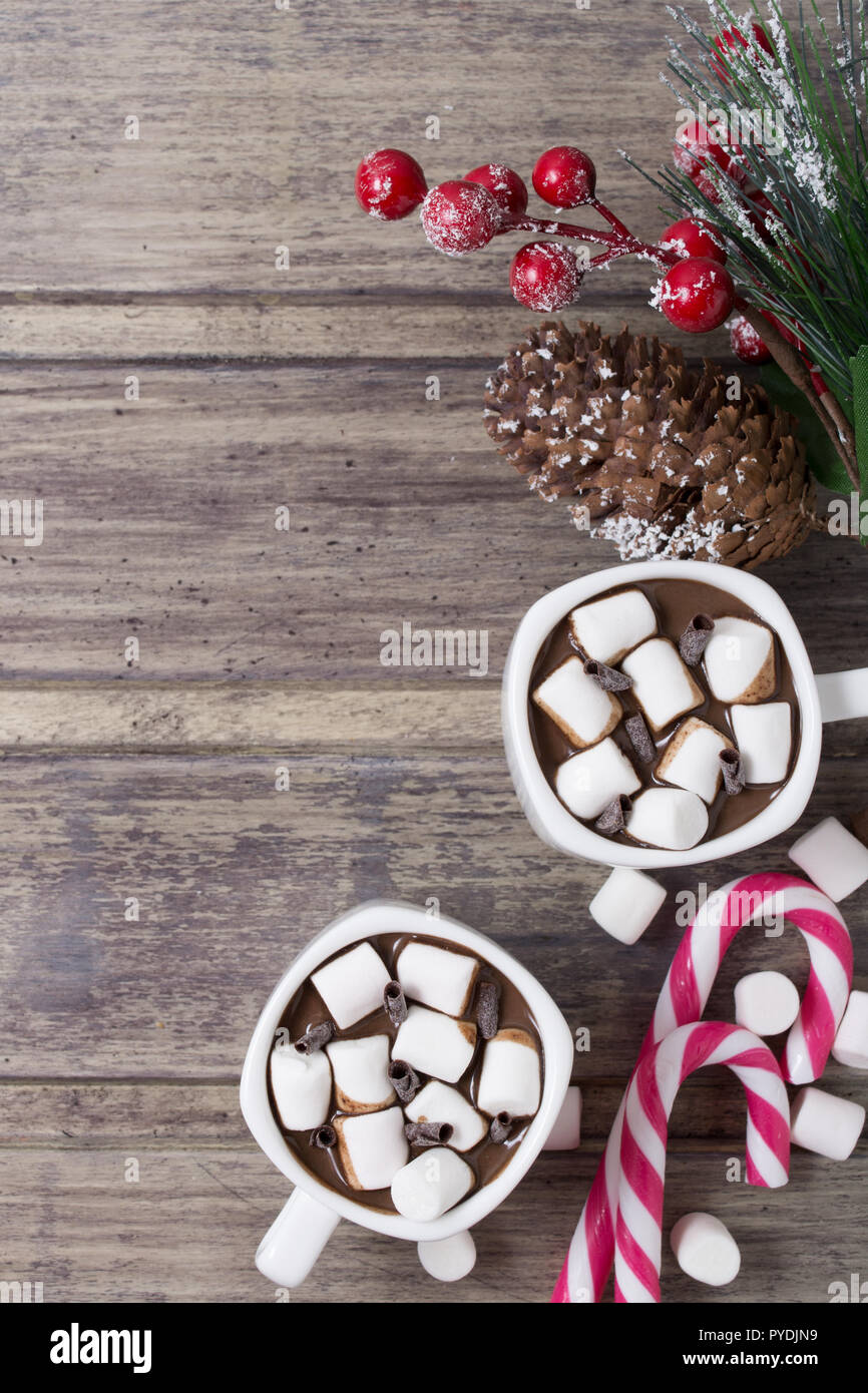 Natale ancora in vita - due tazze di cioccolata calda con marshmallow, caramelle e il ramo di abete con bacche. Spazio di copia Foto Stock