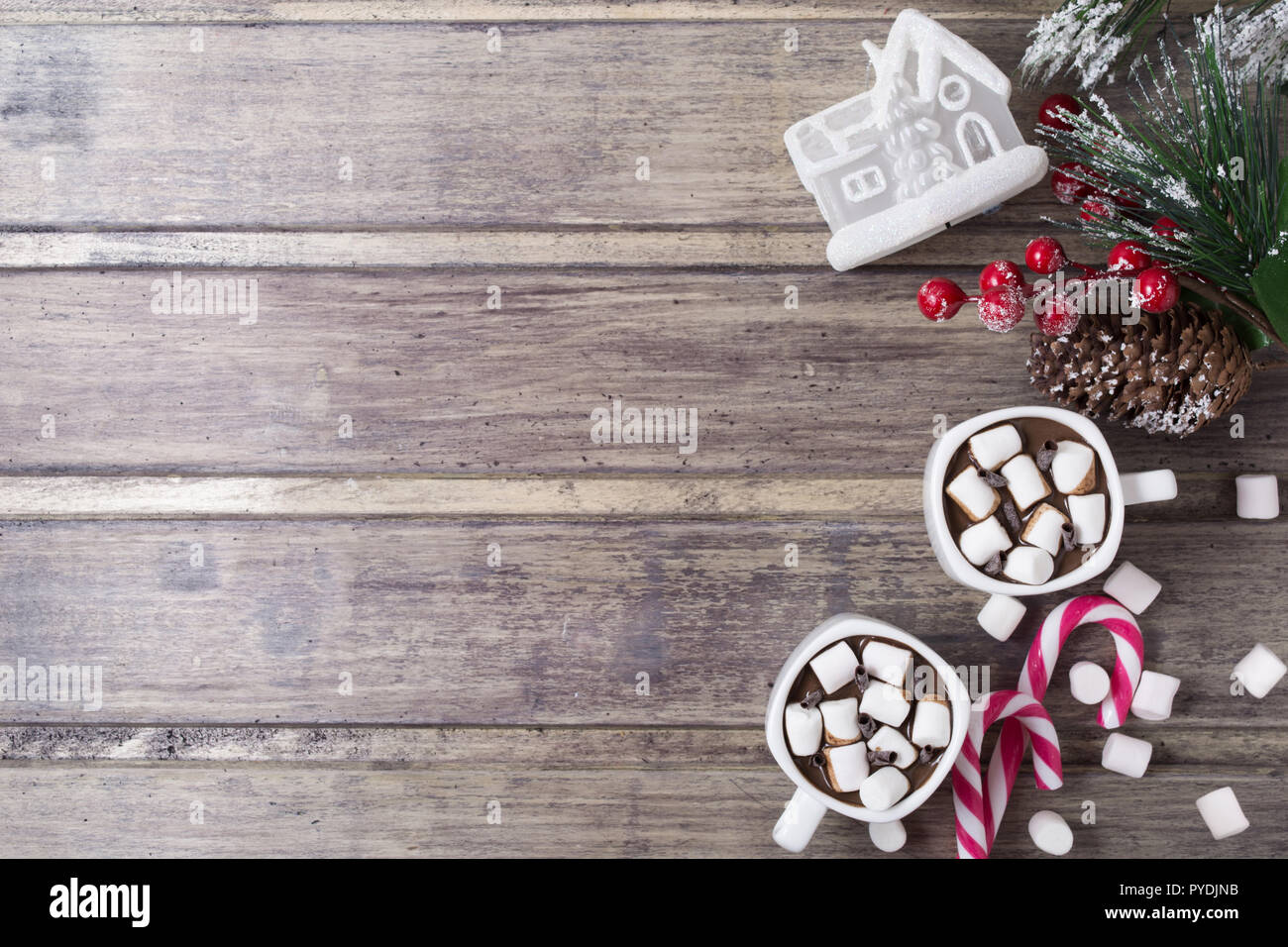 Natale ancora in vita - due tazze di cioccolata calda con marshmallow, caramelle, casa del giocattolo e il ramo di abete con bacche. Spazio di copia Foto Stock