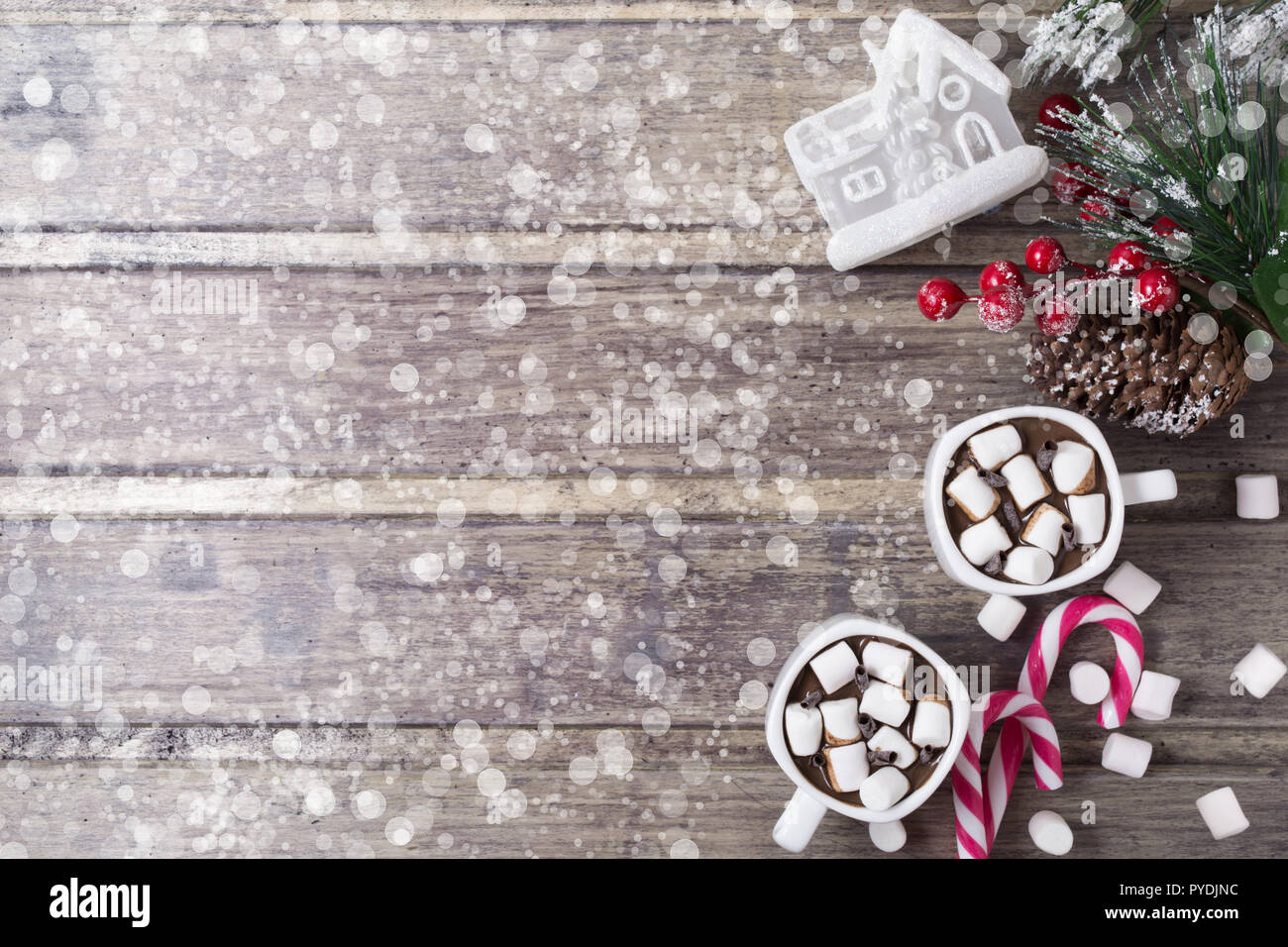Natale ancora in vita - due tazze di cioccolata calda con marshmallow, caramelle, casa del giocattolo e il ramo di abete con bacche. Spazio di copia Foto Stock