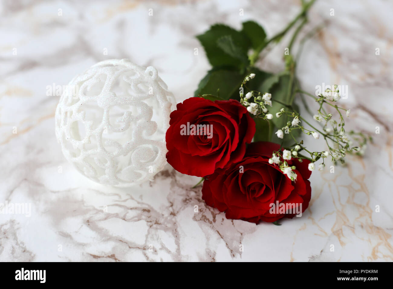 Fiori rossi e bianchi con belle glittery decorazioni di Natale. Fotografato su un marmo bianco superficie. Una vita ancora foto con tema natalizio. Foto Stock