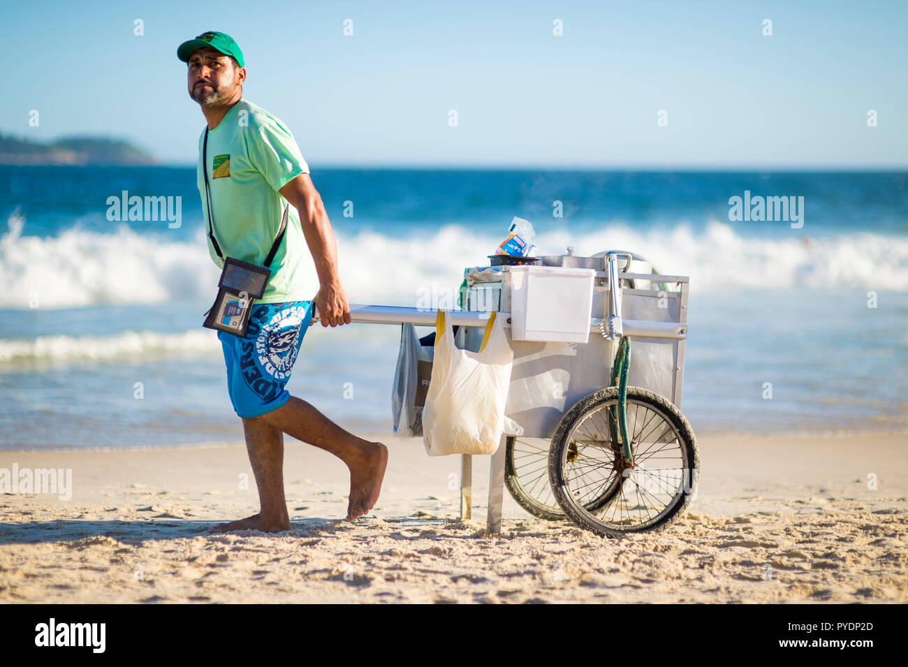RIO DE JANEIRO - circa Febbraio, 2018: una spiaggia brasiliana venditore a vendere il mais bollito ruote di un carrello di acqua calda lungo la spiaggia di Ipanema. Foto Stock