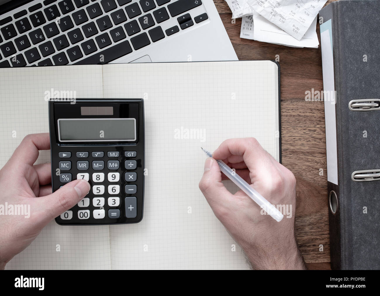 Vista superiore dell'uomo utilizzando la calcolatrice sulla scrivania con cartella, ricevute o fatture e il computer portatile Foto Stock