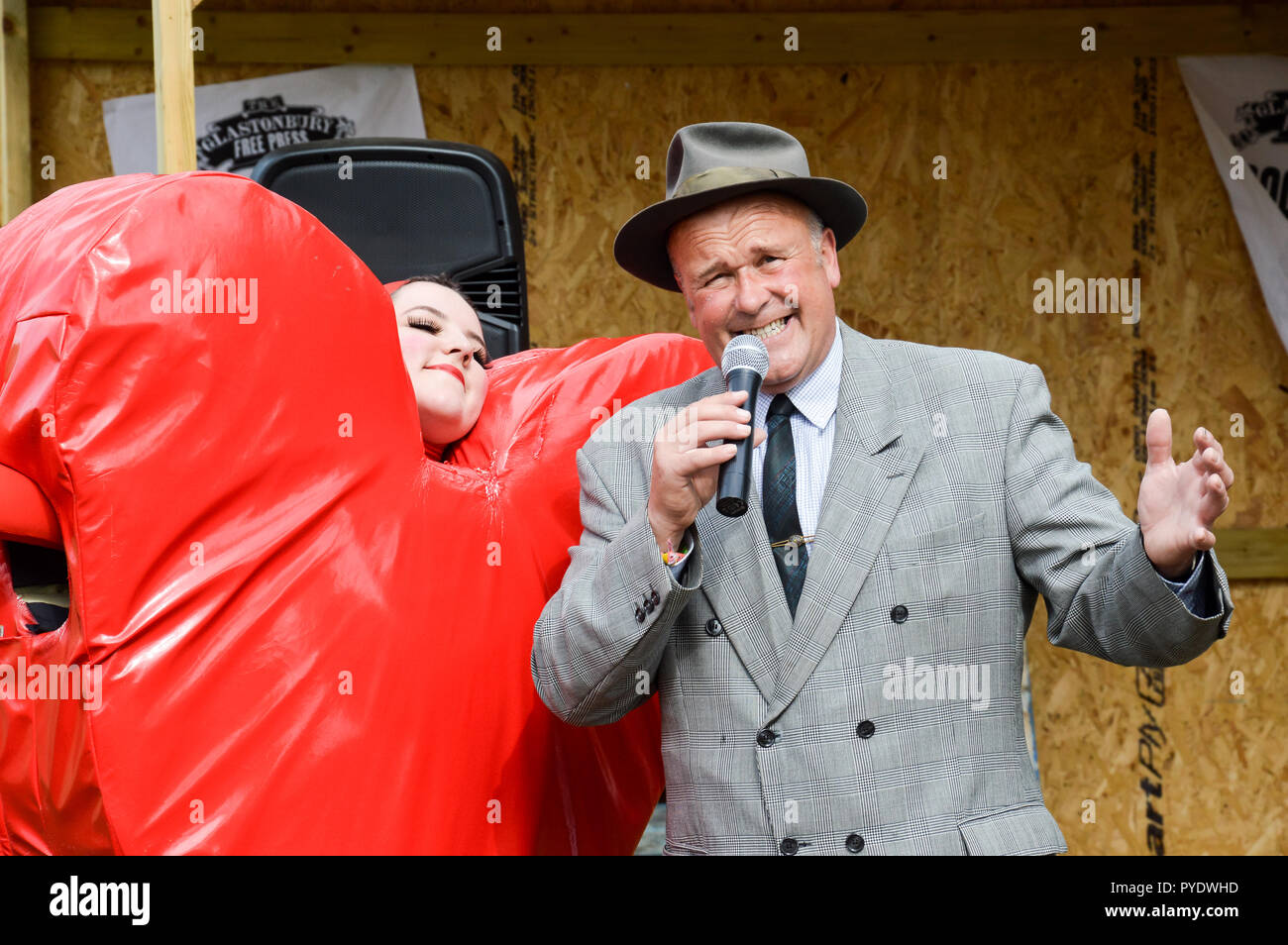 Giugno 28th, 2015.festival di Glastonbury, Regno Unito. Un cantante uomo vestito come un 1940s crooner. Il canto a Glastonbury accanto a una donna vestita come un cuore rosso Foto Stock