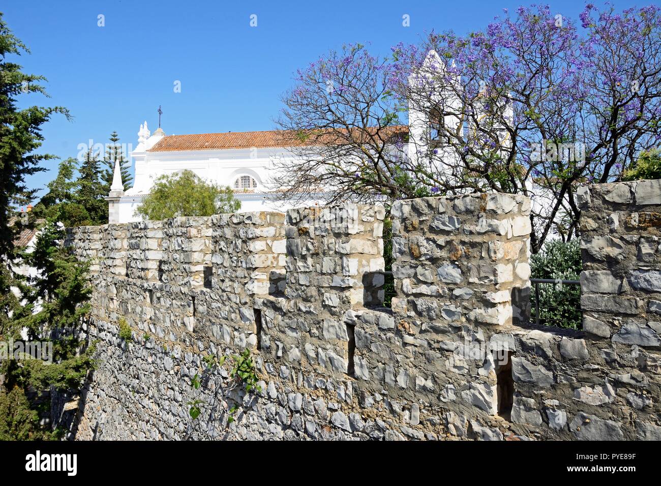 Vista sul castello di merlature con St Marys chiesa (Igreja de Santa Maria do Castelo) verso la parte posteriore, Tavira, Algarve, Portogallo, dell'Europa. Foto Stock