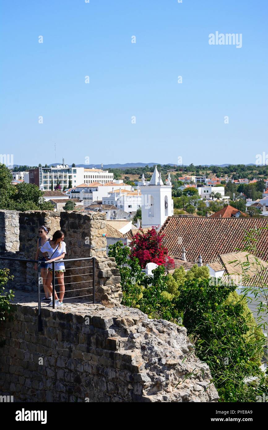 Due giovani donne in piedi sul castello merlature con edifici del comune per la parte posteriore, Tavira, Algarve, Portogallo, dell'Europa. Foto Stock