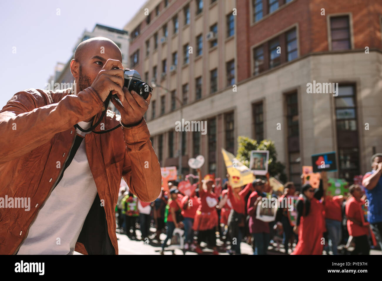 Giovane fotografo prende le immagini degli attivisti holding con segni di slogan. L'uomo prendendo fotografie di un rally su strada della citta'. Foto Stock