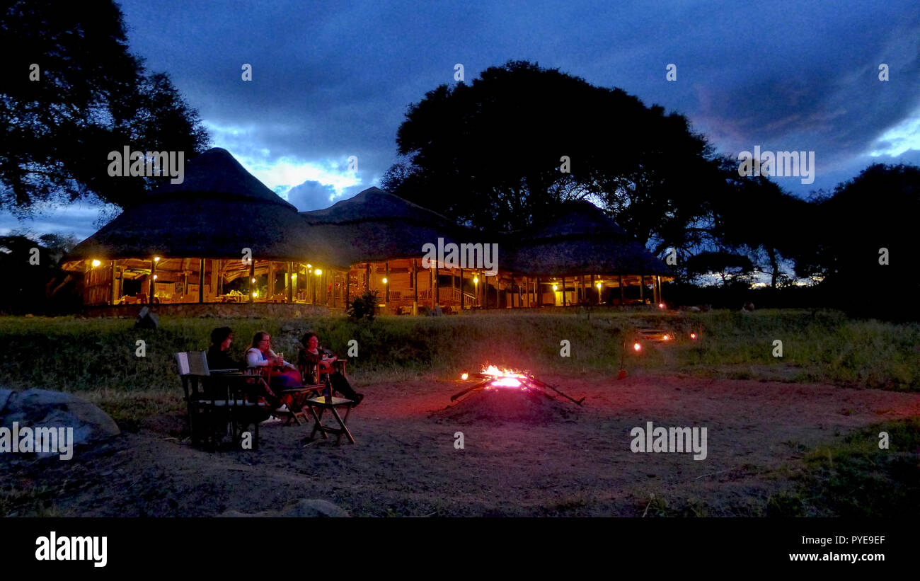 Giorni alla fine in un safari camp seduti intorno al fuoco di rivivere i giorni avvistamenti e memorie Foto Stock