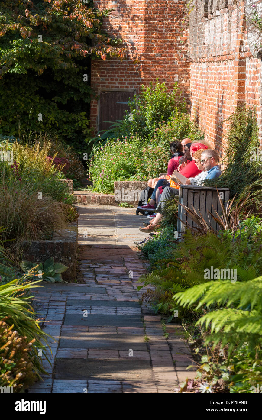 Visitatori e gente seduta in un giardino murato presso il palazzo del vescovo di giardini in Chichester Cathedral motivi in una giornata di sole in west sussex. Foto Stock
