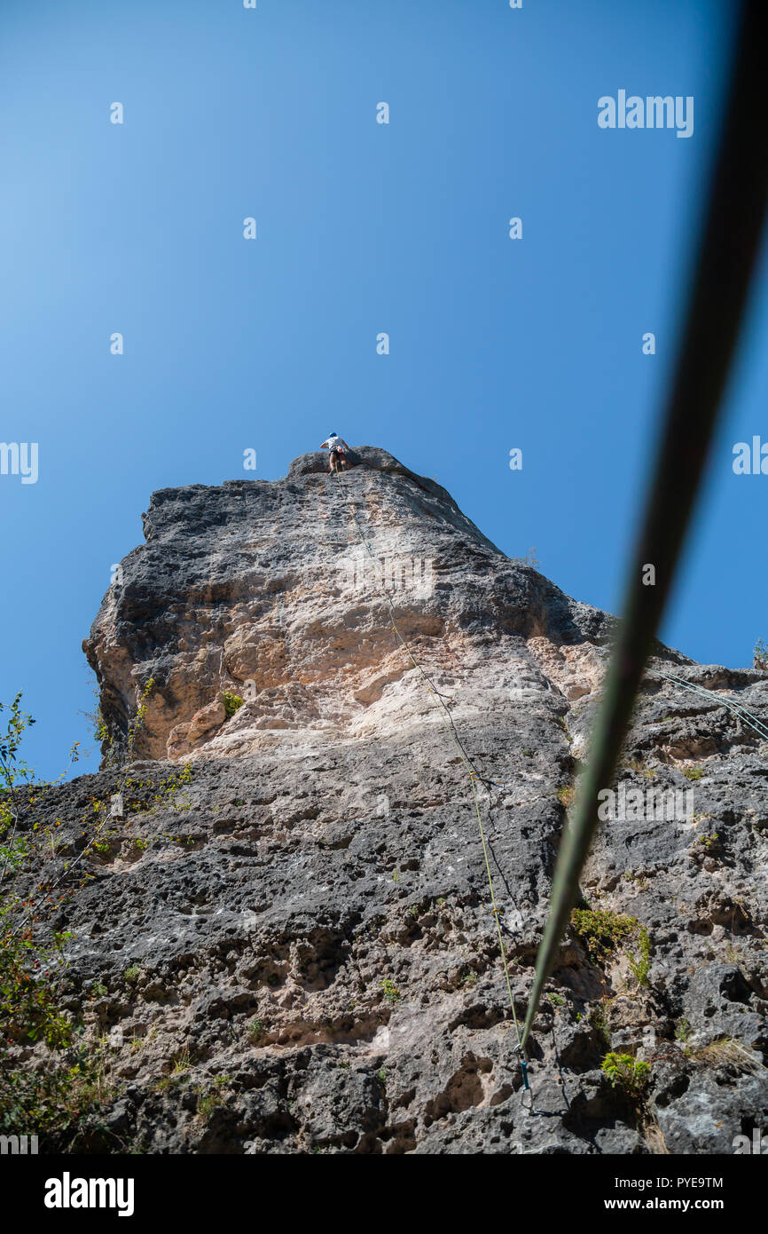 Anonimo scalatore uomo arrampicata in montagna sulla parete incredibile giornata di sole Foto Stock