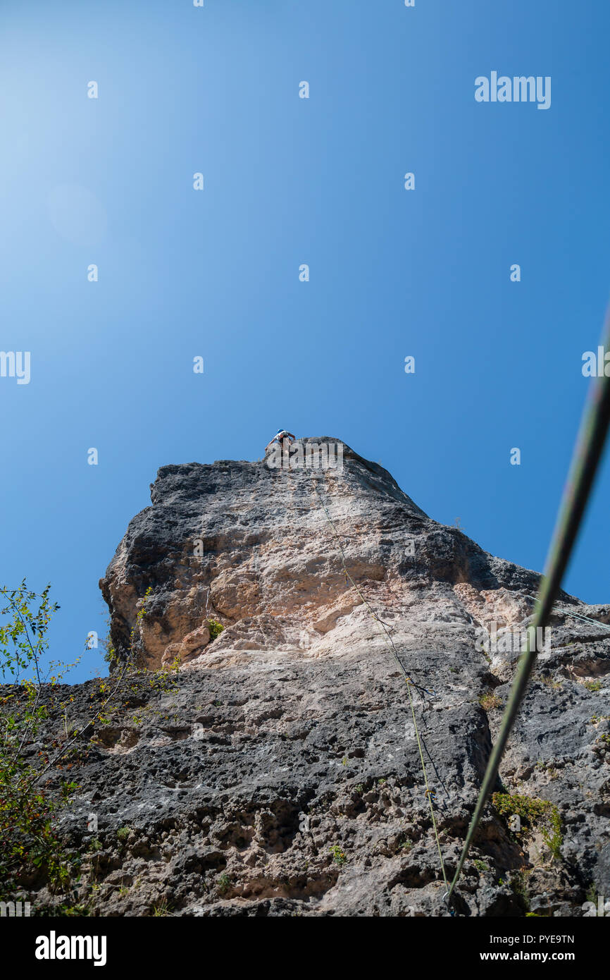 Anonimo scalatore uomo arrampicata in montagna sulla parete incredibile giornata di sole Foto Stock