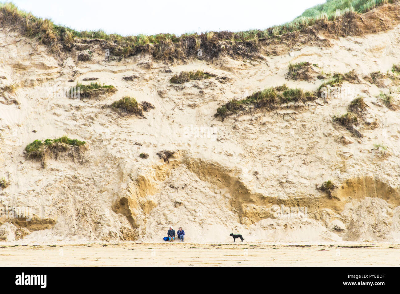 Crantock Beach in Newquay in Cornovaglia - Le persone e il loro cane seduto ai piedi del sistema di dune. Foto Stock