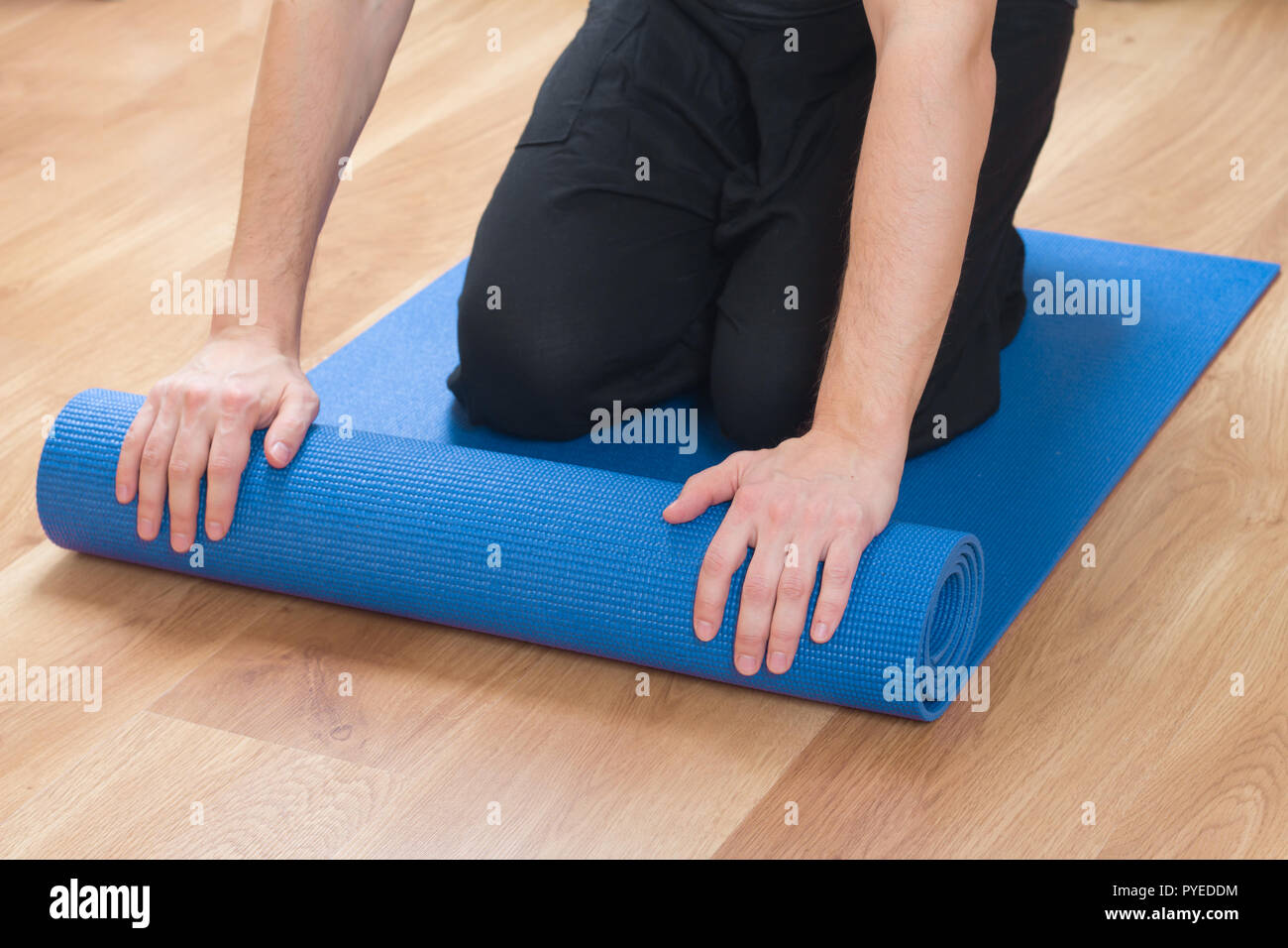 Primo piano delle mani di uomo esercizio di rotolamento materassino yoga Foto Stock