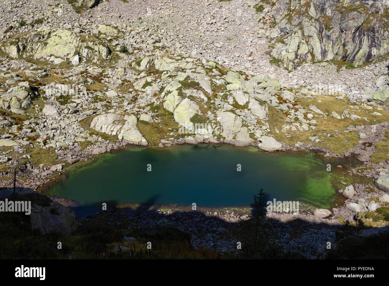 Autunno escursionismo in Valle d'Aosta, Gressoney, Italia. Vista del lago alpino di Goudin descendig dal Passo Sella. Il percorso è già in ombra. Foto Stock