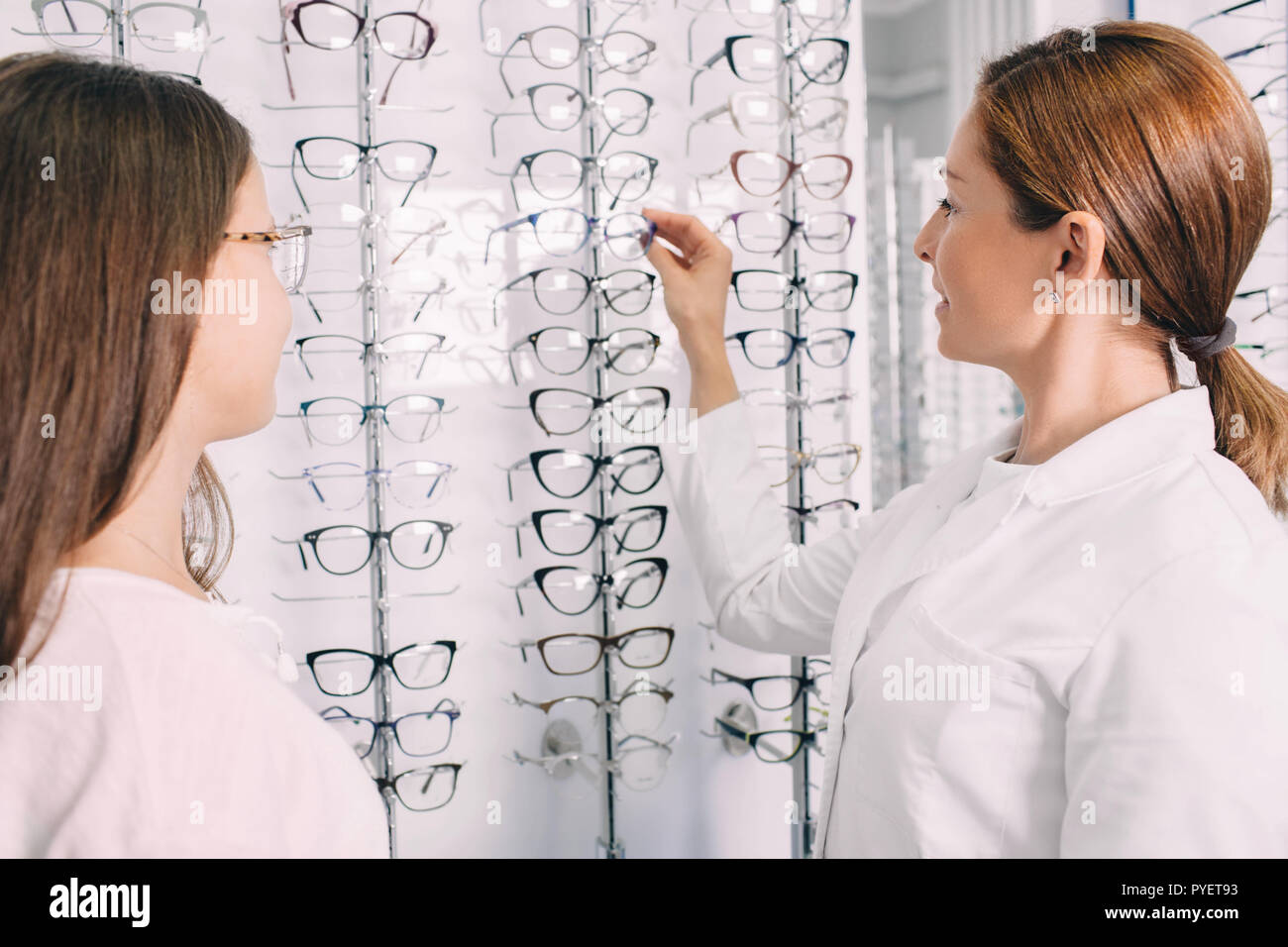 Il farmacista counseling ragazza adolescente in negozio, che tipo di occhiali per scegliere Foto Stock