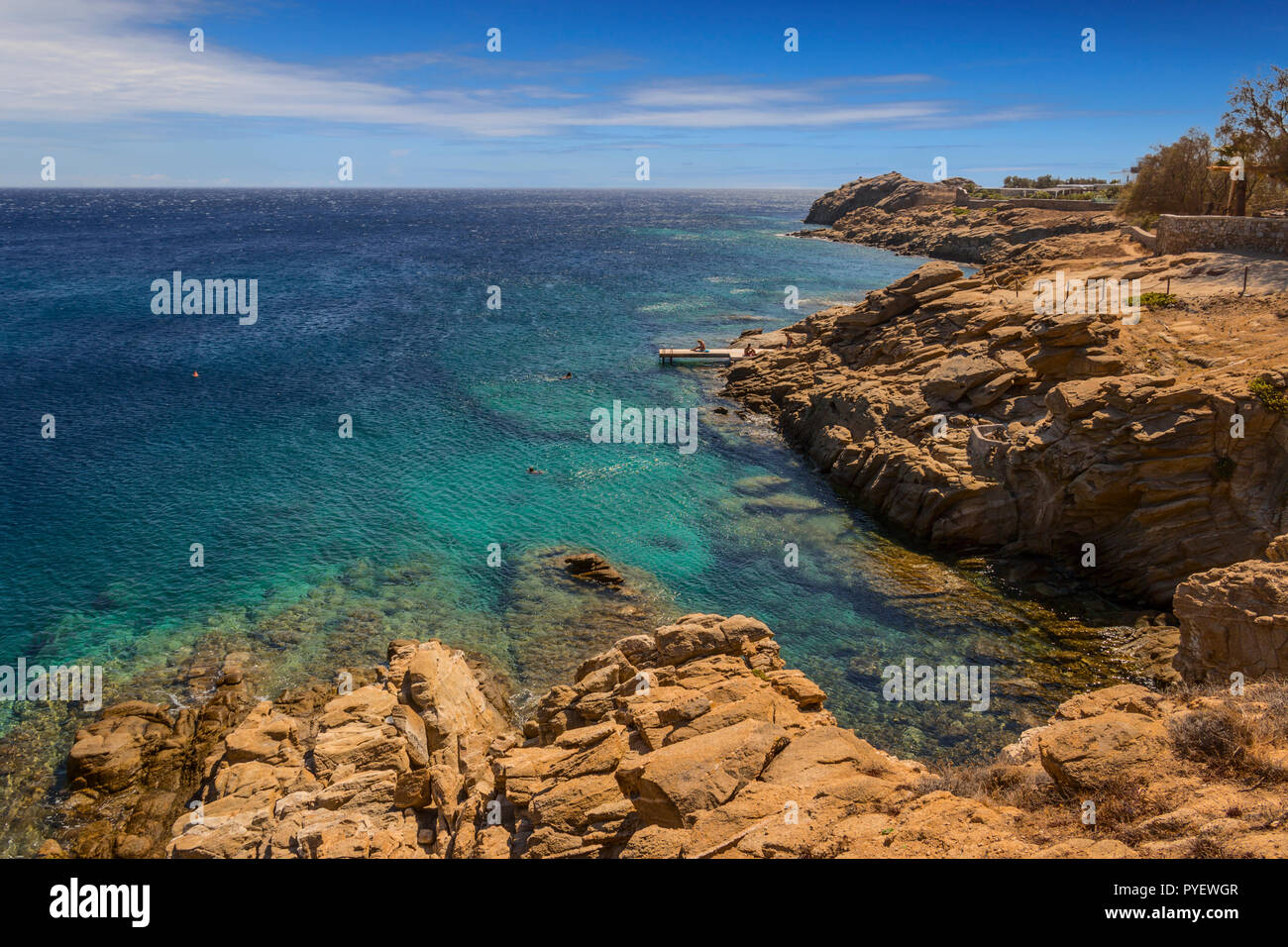 Estate: isola di Mykonos, Grecia. Lo splendido paesaggio della costa rocciosa: acque azzurre del Mar Egeo, Cliff, pietre e sassi. Soleggiato con cielo blu e Foto Stock