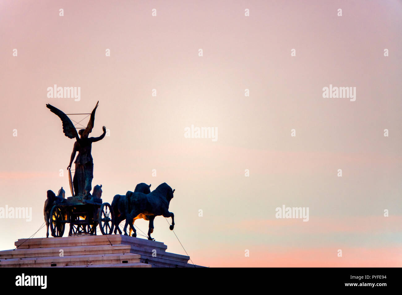 Statua della Dea Victoria a cavallo su quadriga sulla sommità del monumento a Vittorio Emanuele II al tramonto, Roma, Italia Foto Stock