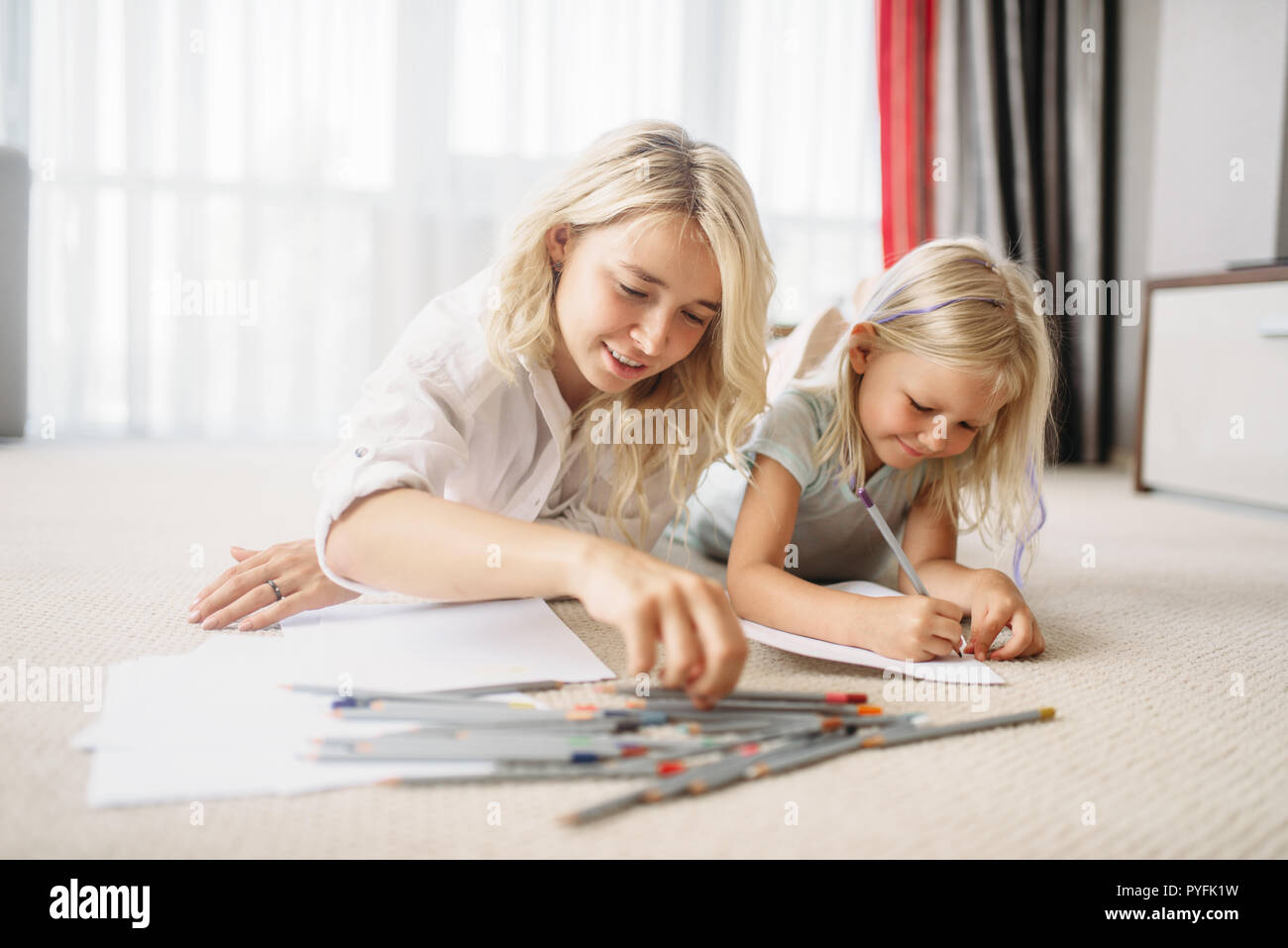 La madre e il bambino disegna sdraiato sul pavimento. Sensazione di genitore, stare insieme Foto Stock