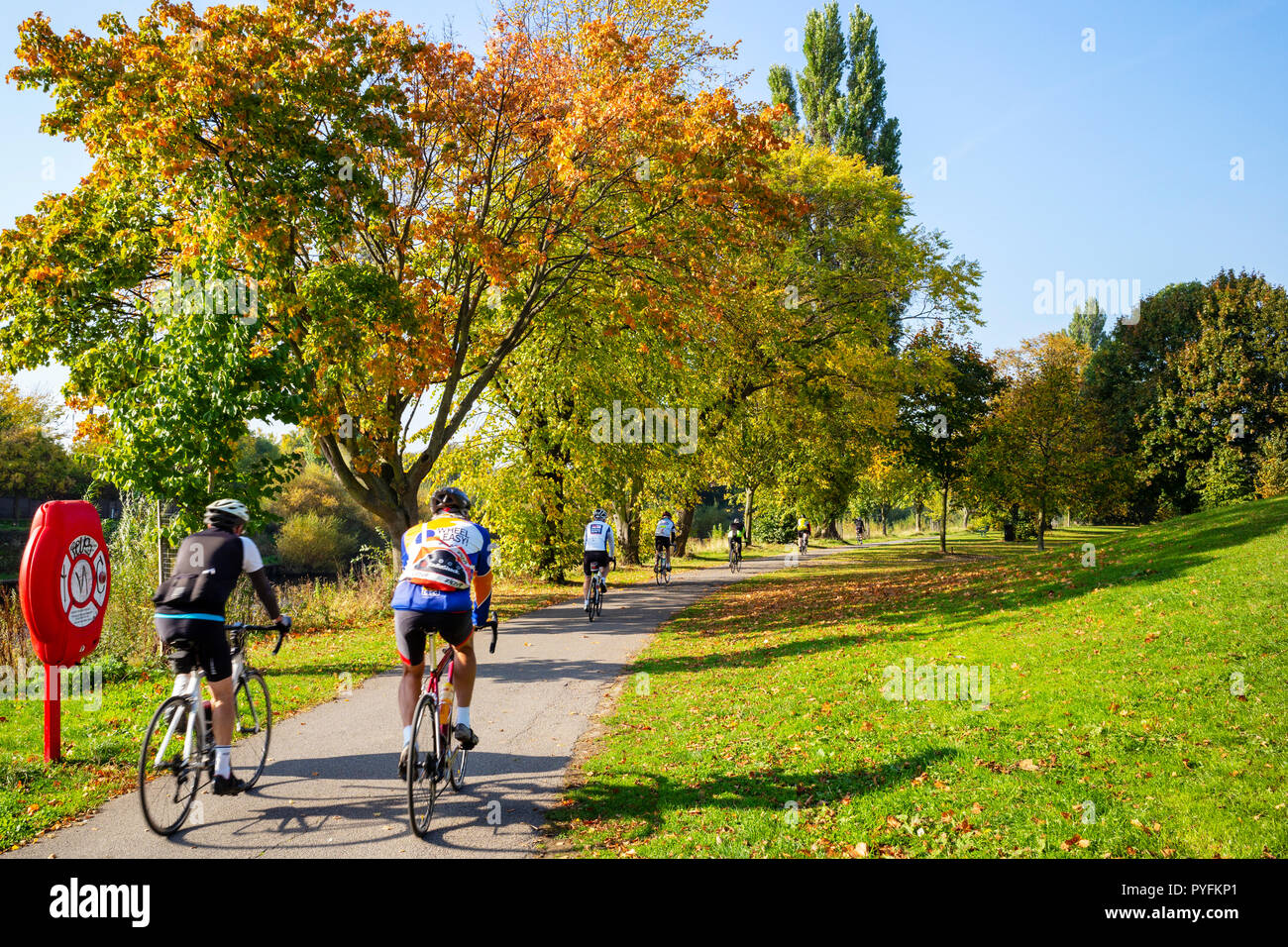 I ciclisti approfittando di una soleggiata giornata autunnale accanto al fiume Ouse in York, nello Yorkshire, Regno Unito Foto Stock