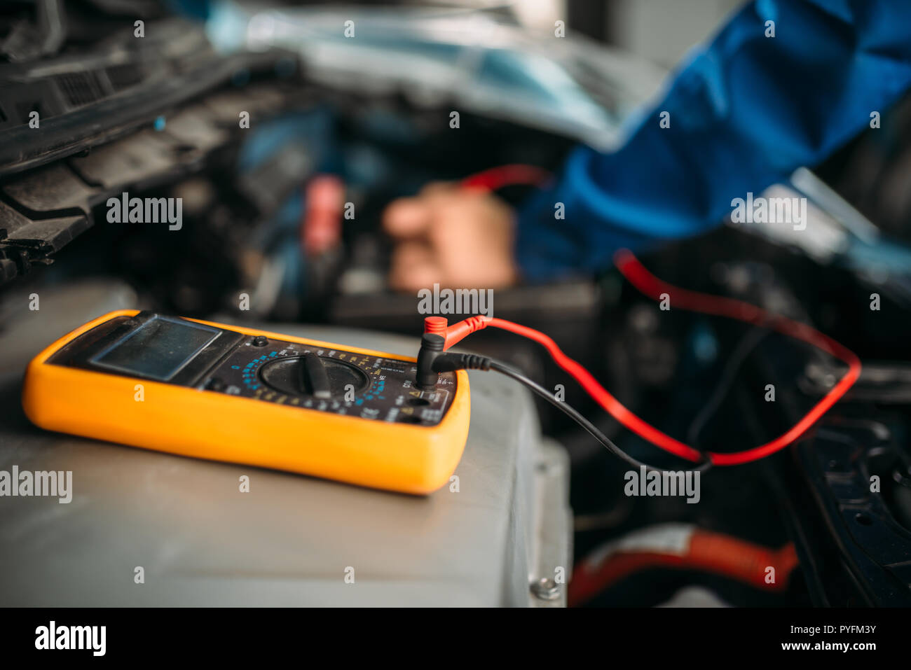 Car repairman con multimetro, Ispezione della batteria. Auto-service, cablaggio del veicolo Diagnostica, elettricista professione Foto Stock