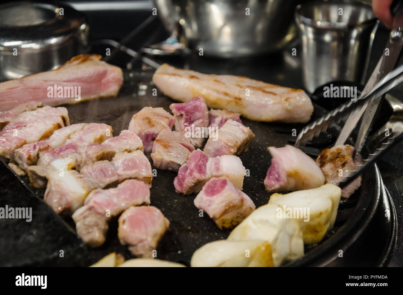 La carne di maiale per la cottura su un barbeque Coreano, un tradizionale pasto in un ristorante coreano. Foto Stock