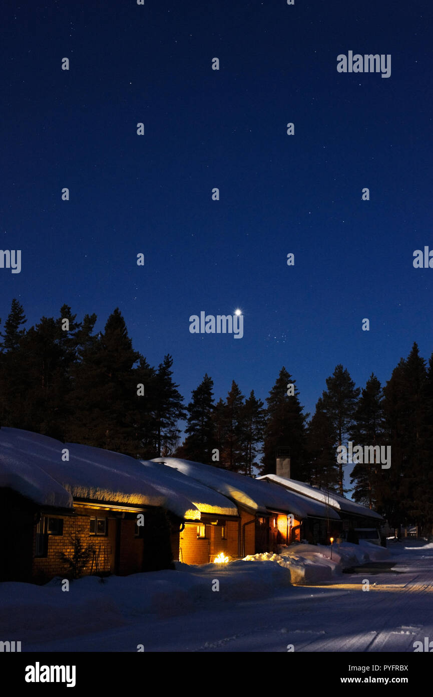 Villetta a schiera in inverno nevoso di notte. Il pianeta Venere e le Pleiadi nel cielo stellato. Foto Stock