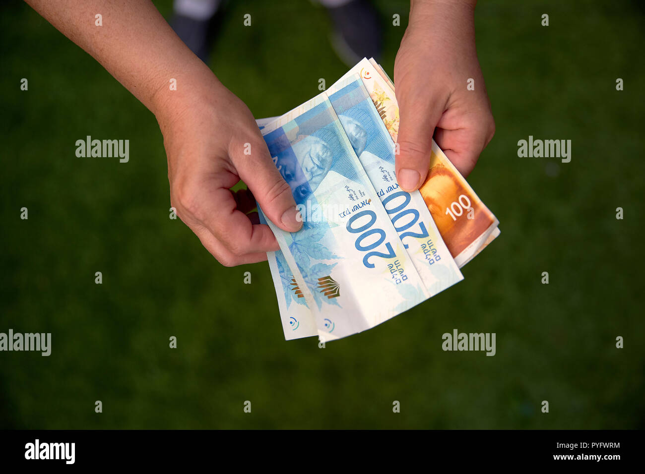 Donna che mantiene un mazzetto di nuovo Israeli Shekel banconote nelle sue mani Foto Stock