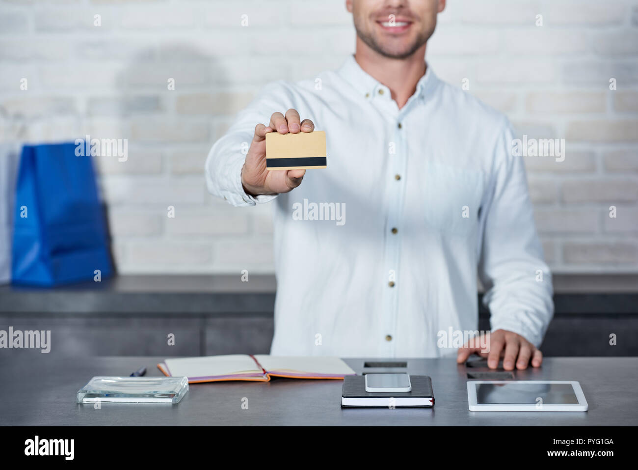 Ritagliato shot di sorridere giovane venditore tenendo la carta di credito in negozio Foto Stock