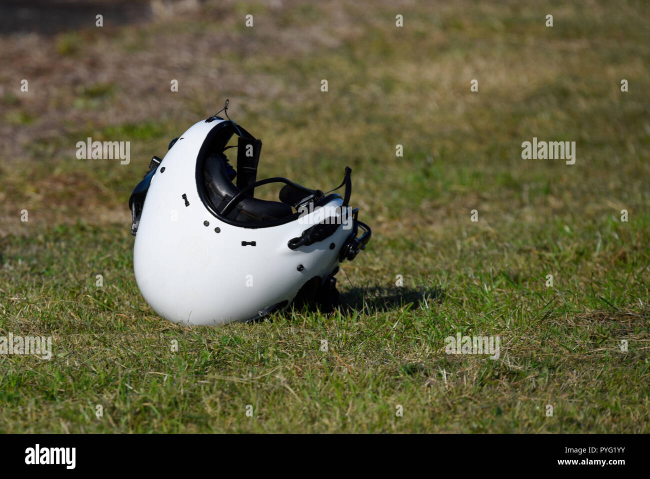 Un casco volante anonimo seduto sull'erba senza pilota. Pilota mancante. Scartato. Equipaggiamento volante isolato Foto Stock