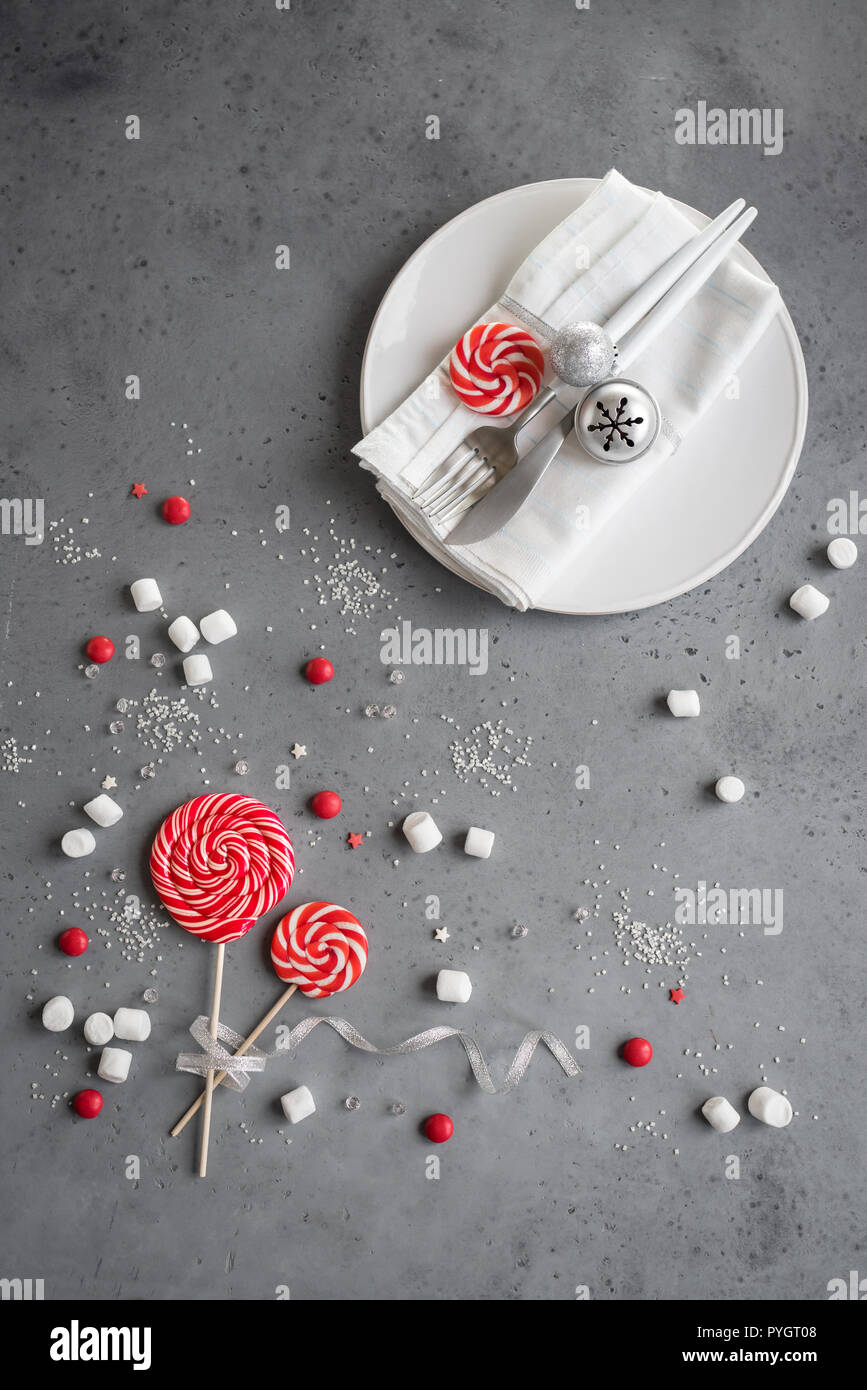 Tavola di natale con impostazione di colore rosso e bianco inverno stagionali dolci su grigio, copia dello spazio. Cena di Natale, festa desigh, concetto. Foto Stock