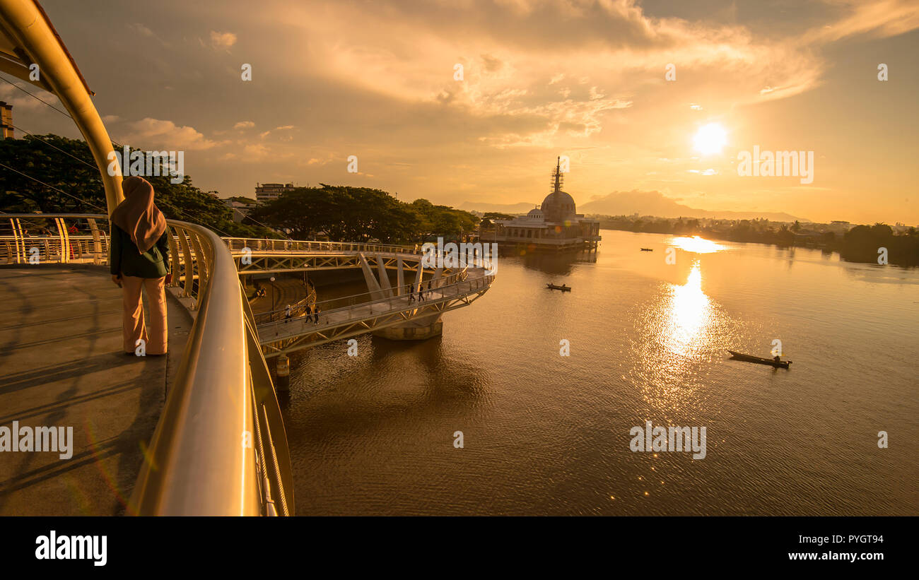 Vista era preso durante il tramonto sulla passerella pedonale chiamato Darul Hana. La città di Kuching sull'isola del Borneo è divisa dal fiume Sarawak. Foto Stock