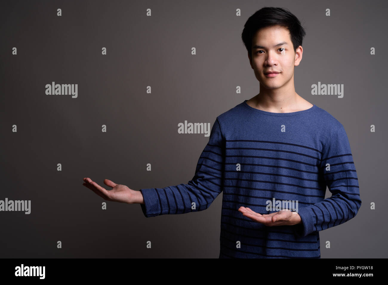Bel giovane uomo asiatico che mostra lo spazio di copia Foto Stock
